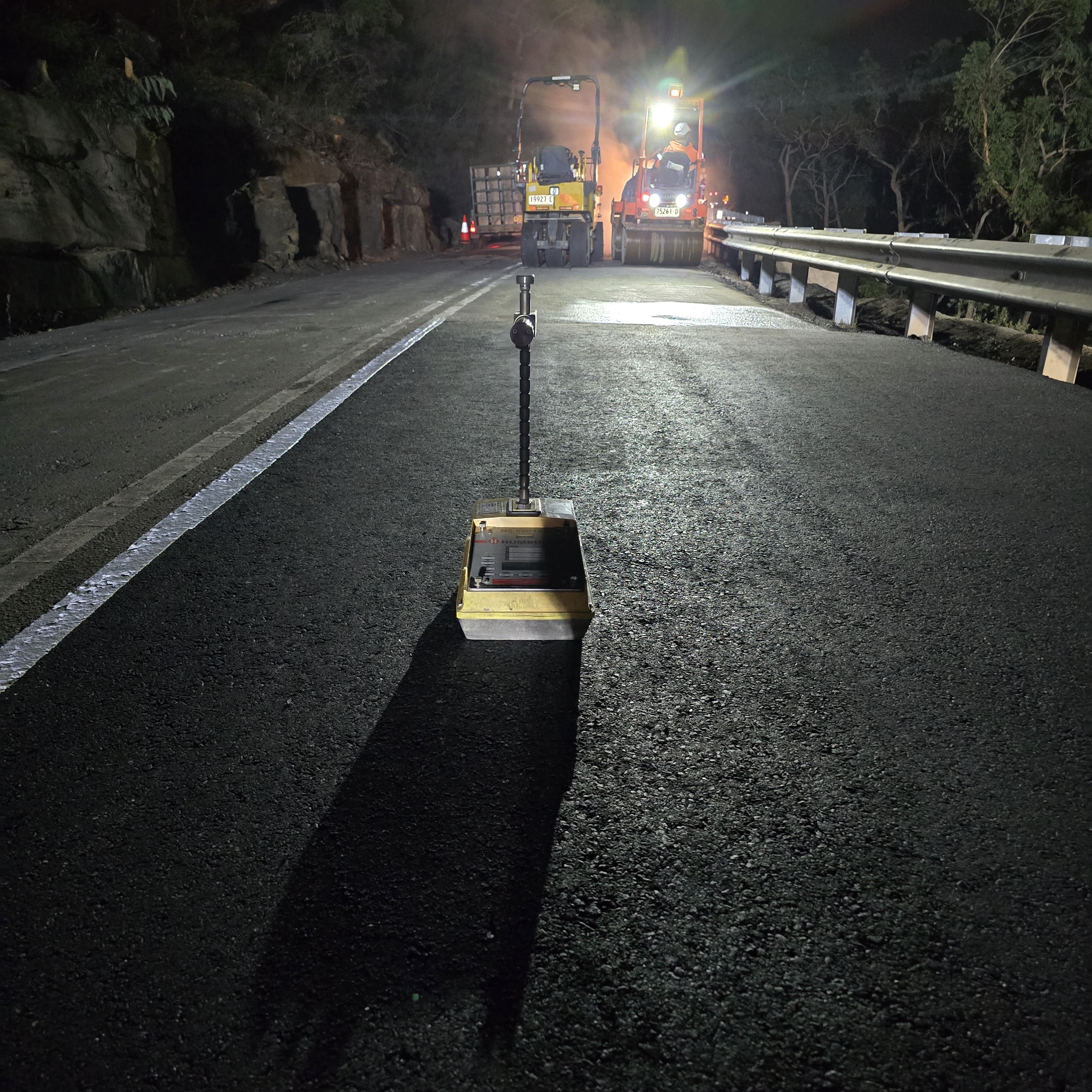 Nuclear density gauge in use during night asphalt paving works